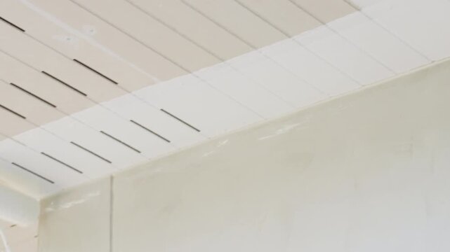 Closeup of homeowner painting ceiling using roller brush. DIY home improvement project, interior renovation and house maintenance concept. Simple repair and decorating work inside residential room.