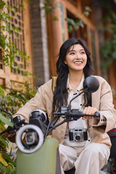 Happy young woman rides a shared electric motorcycle