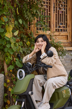 Happy young woman rides a shared electric motorcycle