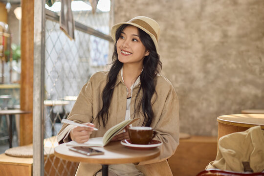 Happy young woman enjoys herself in a cozy caf��