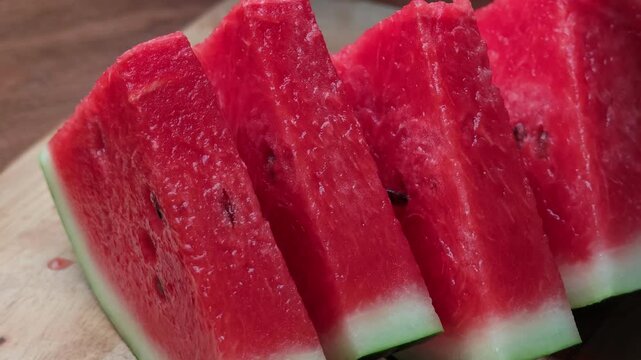 Closeup of hands cutting watermelon on the board.