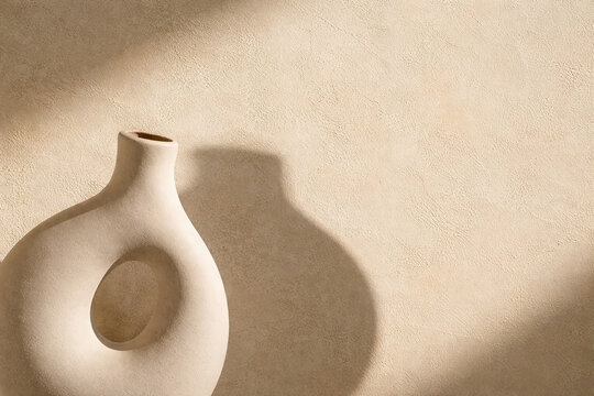 Minimalist ceramic vase shadow on beige limewash wall