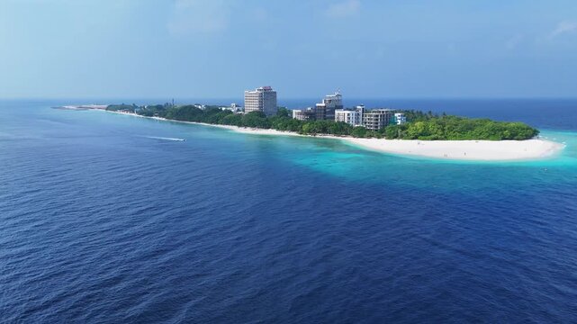 Distant drone view of the long Ukulhas shoreline in the Maldives. This wide angle reveals the striking contrast between the turquoise ocean, white sand, and modern island construction.