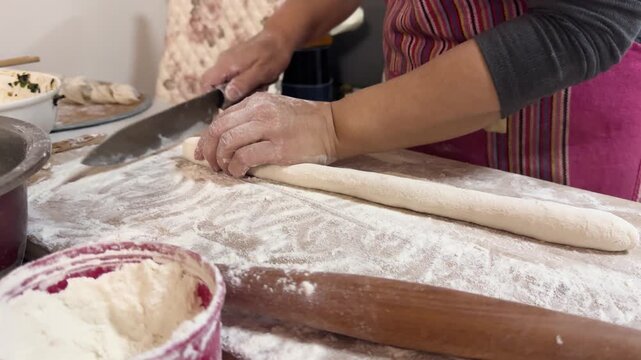 Hands rolling out dough with a wooden rolling pin on a floured board, preparing dumpling wrappers from scratch in a home kitchen for a festive meal in Xi'an, China.