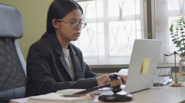 Professional business woman working on laptop in modern office workspace. Focused female employee typing on computer during workday representing corporate career, productivity and technology.