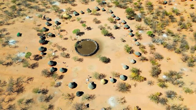 Aerial drone view of a traditional circular Himba village settlement in northern Namibia with huts arranged around a central livestock enclosure