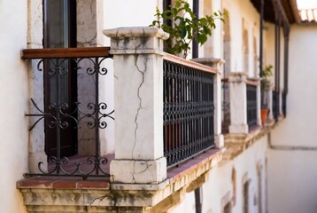 Fototapeta premium A weathered balcony with a wrought-iron fence and potted citrus tree, in an old Mediterranean building.