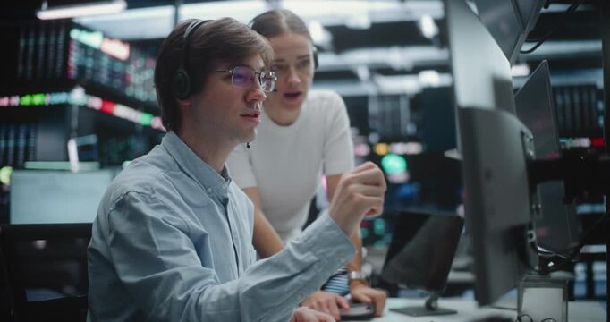 Financial Analysts Collaborating and Discussing Market Trends at Trading Desk. Male Trader in Glasses and Female Colleague With Headset Work Together Multi Monitor Workstation. Market Analysis.
