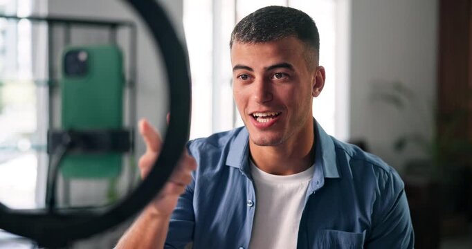 Phone, ring light and influencer with conversation for live stream, content creation and social media in home. Man, streamer and gen z person with tech for broadcast, chat and online interaction