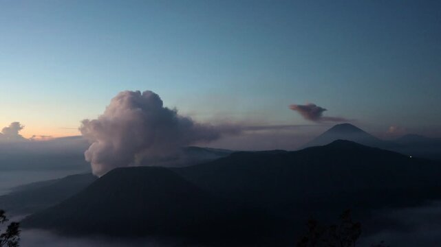 Wide shot B-Roll of Gunung Batok Cinder Cone with Mount Bromo Eruption and mount Semeru in background at Sunrise | King Kong Hill, East Java, Indonesia