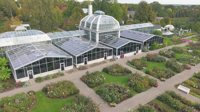 Stunning aerial footage of VDU Botanical Garden greenhouse, showcasing lush gardens and intricate architecture in vibrant Kaunas. Sunlit and serene, ideal for nature enthusiasts.
