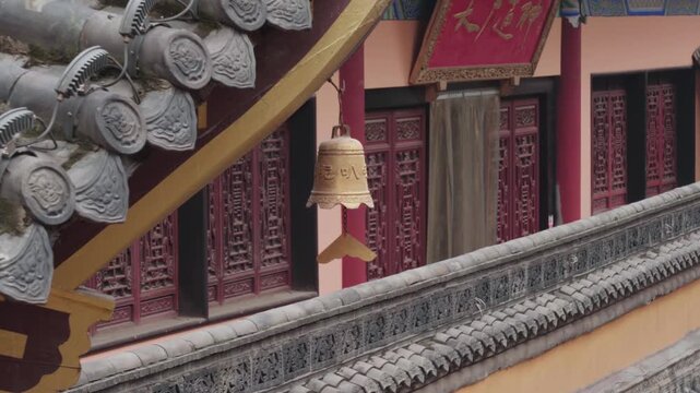 Static close view of a traditional hanging bell beneath a tiled roof at Luohan Temple in Chongqing, China, showing classic Chinese Buddhist temple architecture and decorative cultural element