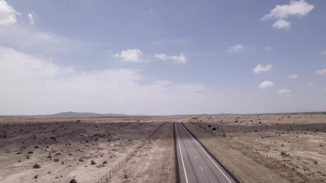 An empty highway cutting through the stark west Texas desert, aerial view