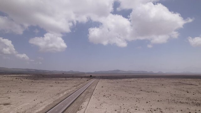 Cloud shadows move across an empty highway in the west Texas desert, aerial view push in