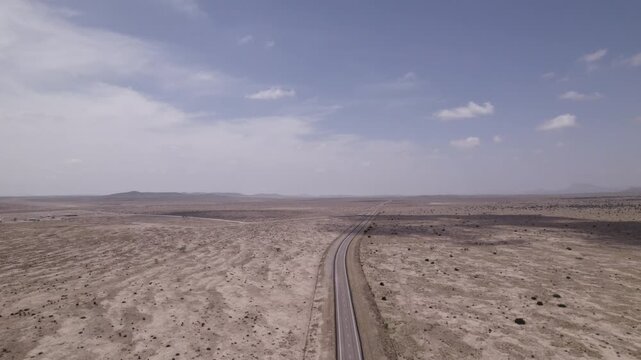 An empty highway cutting through the stark west Texas desert, slow aerial view