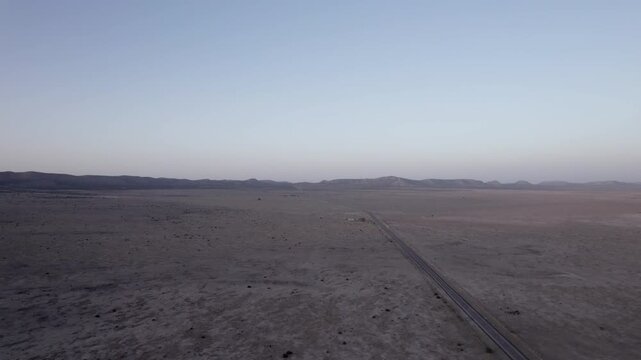 A vast west Texas desert landscape with an empty highway cutting through it, aerial view