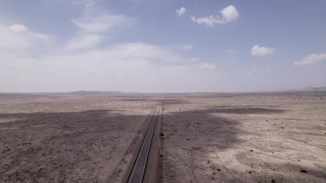Cloud shadows move across an empty highway in the west Texas desert, slow drone view of the landscape
