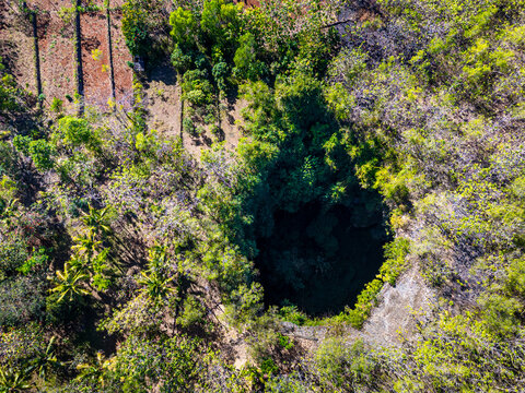 Jomblang cave in Gunungkidul is a doline formed by a cave collapse a large, natural sinkhole with steep edges surrounded by trees. Geological formations and natural land changes, drone view, aerial.