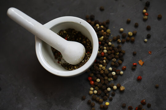 Mortar and Pestle with Mixed Peppercorns on Dark Slate Background