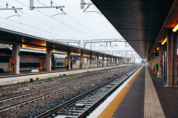 Train station with empty platforms and tracks during a cloudy day