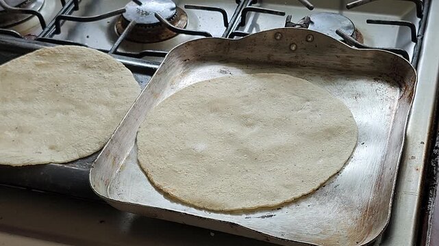 Corn tortilla cooking on a traditional hot griddle