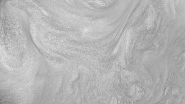 Flowing silver abstract background. Liquid silver moves in waves and swirls. Beautiful shiny grey texture with glitter. Liquid silver metallic paint in motion. Shimmer in slow motion.