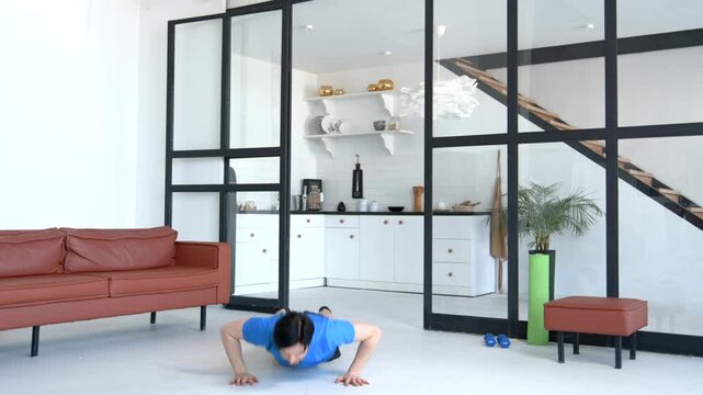 Motivated active fit handsome man in sportswear doing burpees workout, strengthening body muscles, improving heart rate and blood flow while exercising in domestic room.