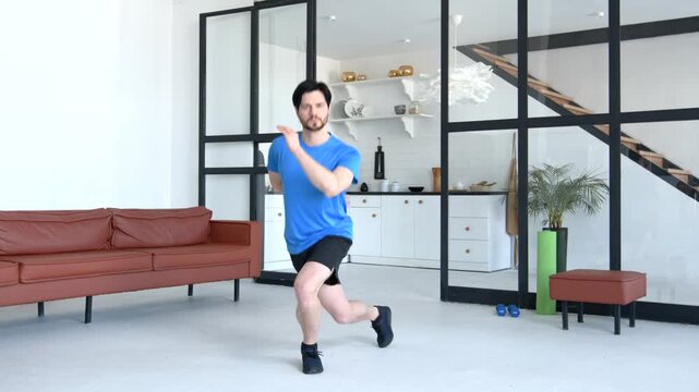 Determined sporty fitness man working out skater lunges exercise, strengthening glutes, hamstrings and inner thighs while practicing indoor sports training in domestic room.