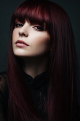 Fototapeta premium studio portrait of a female model with straight burgundy colored hair and bangs