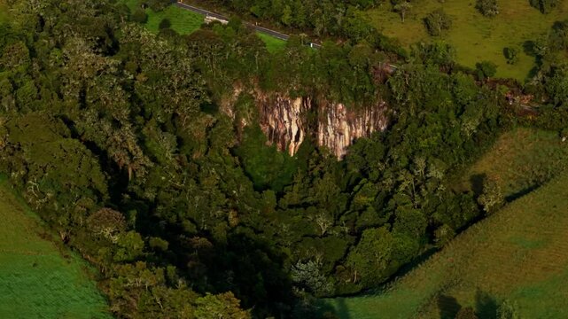 Aerial view of a lush green valley with a rocky cliff in nevado del ruiz national park, colombia