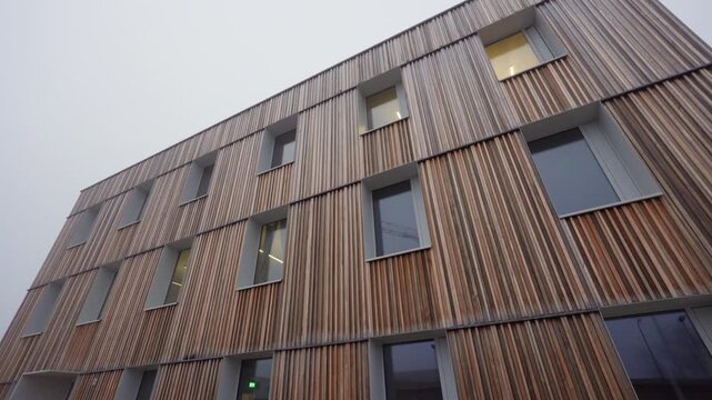 Modern office building shows a wooden facade with windows in daylight