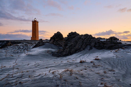 Lighthouse guiding through a dramatic volcanic coastal landscape