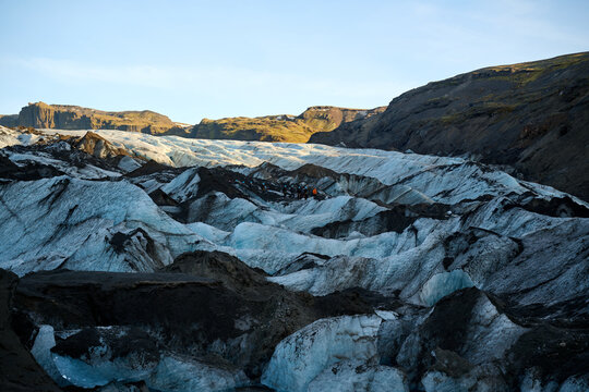 Glacier landscape with hiker walking across ice and ash