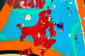 Weathered concrete surface with layers of red blue and orange spray paint. Abstract urban decay...