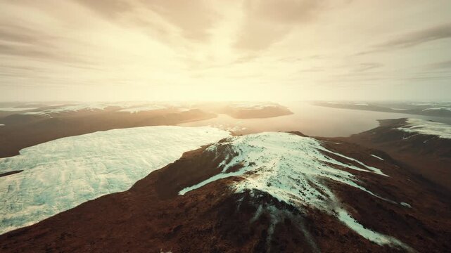 glacier peak silhouette melting into dusk light, steep ridgelines framed by warm horizon, scattered snowfields, atmospheric clouds, melancholic tone suggesting