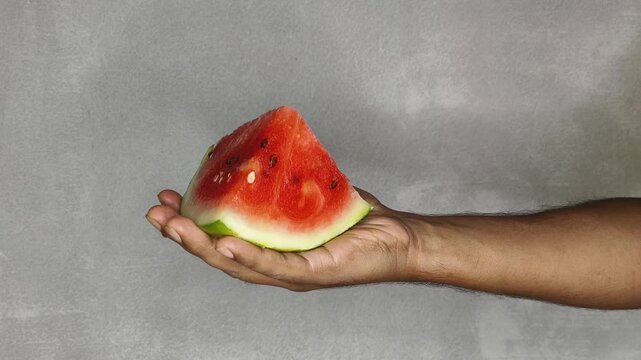 Person hand holding organic ripe juicy red watermelon fruit slice on palm isolated on white background with copy space. Weight loss and healthy diet snack concept. Closeup side view.