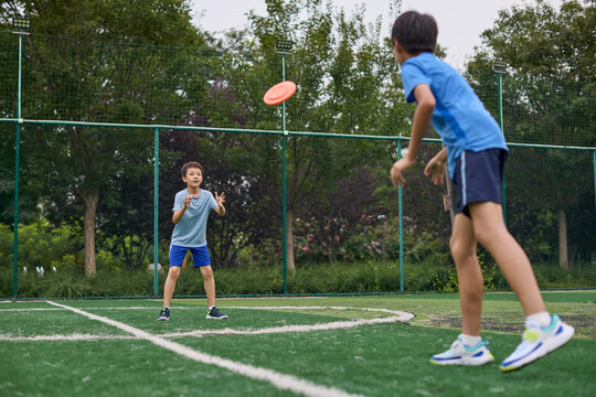 Boys playing frisbee on the tennis court