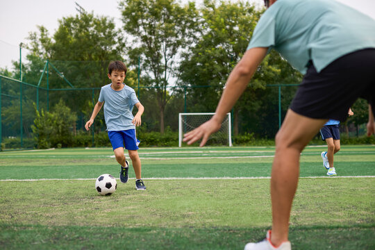 Boys play football under the coach's instruction