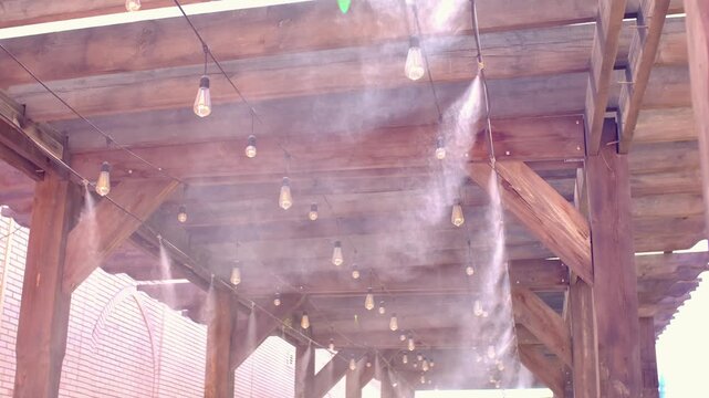 Water spray system for cooling the terrace on a hot summer day. Fogging system, high pressure water spray. Wooden ceiling in loft style.