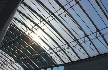 The sun shines through the transparent roof of a large cylindrical hangar

