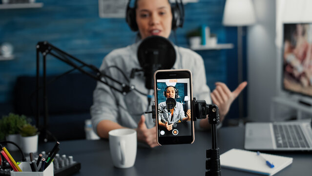 Popular content creator streaming live daily vlog using smartphone while talking to public. Online live radio talk show host discussing last worldwide news and evens with public.