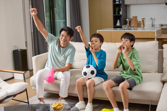 Boys and their dad watching a football game at home