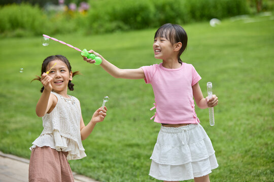 Two girls blowing bubbles in the park