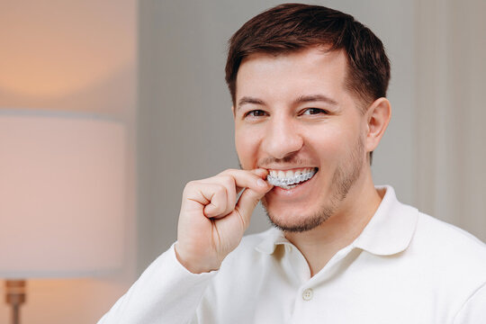Man placing clear aligner for teeth while smiling to show oral care and orthodontic treatment