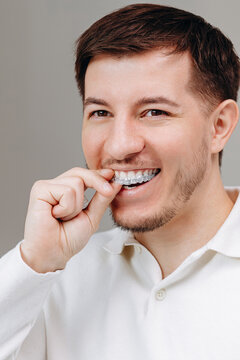 Young man inserting clear aligner tray for teeth, dental care and confident smile at home