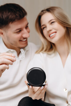 Happy couple holding a clear dental aligner and black carrying case while smiling about orthodontic care