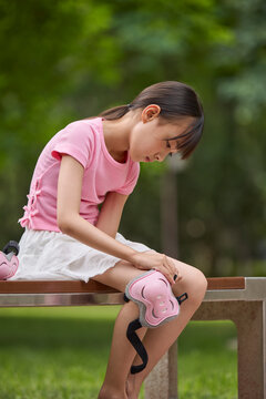 A girl puts on her protective gear for roller skating