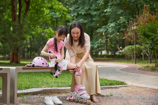 Mother helps her daughter put on her protective gear for roller skating
