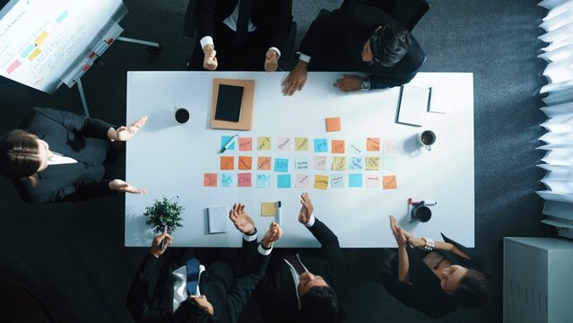Top down ariel view of professional project manager present idea while putting together and clapping hand to celebrate successful strategy at meeting room. Show unity, love, teamwork. Directorate.