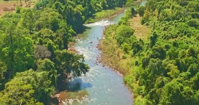 Aerial view of Tad Pha Suam Waterfall near Pakse in Champasak Southern Laos. Water flows over unique column like rock formations surrounded by lush tropical forest, creating a scenic natural